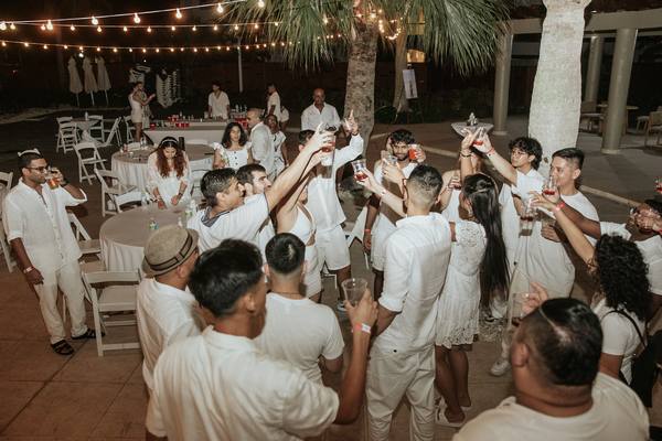Wedding party raising champagne glasses for a sunset toast at an elegant outdoor reception